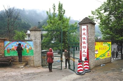 23日，云南丘北县平龙佳佳幼儿园，死者杨梓艺的母亲（中）站在幼儿园门口，园长的老公前来关门。